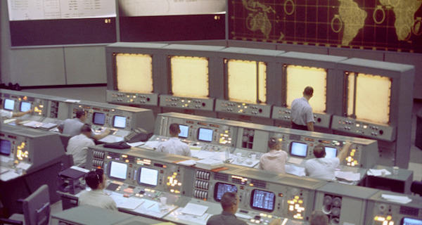 Overall view of the Mission Control Center (MCC), Houston, Texas, during the Gemini 5 flight. Note the screen at the front of the MCC which is used to track the progress of the Gemini spacecraft.