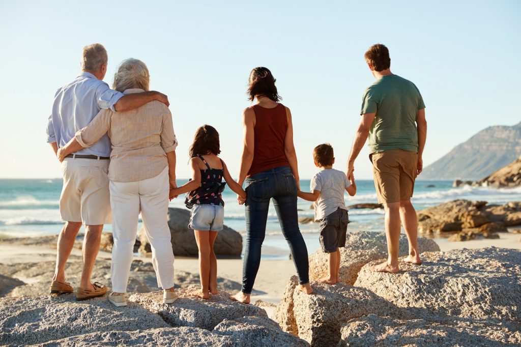 Porodica sastavljena iz tri generacije uživa u pogledu na plaži obučena u odeću za šetnju